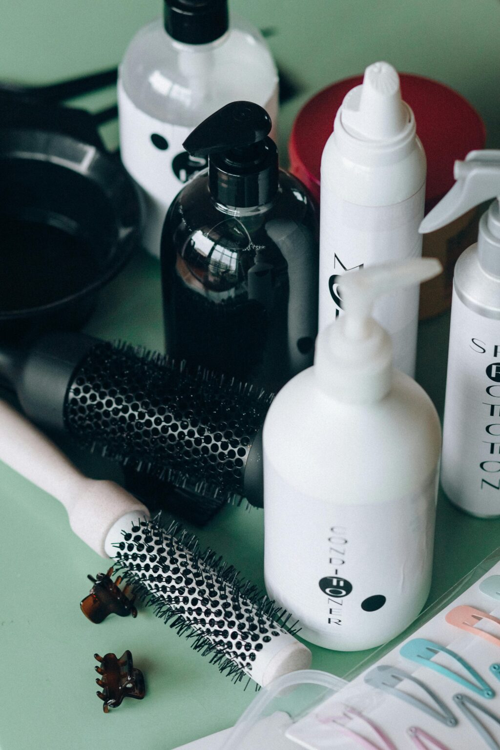 Plusieurs contenants de produits de nettoyage pour chien et des brosses de brushing et des pinces posés sur une table verte